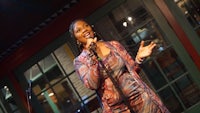 a woman in a colorful dress singing into a microphone
