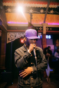 a man in a purple hat singing into a microphone