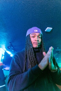 a man with dreadlocks and a purple hat