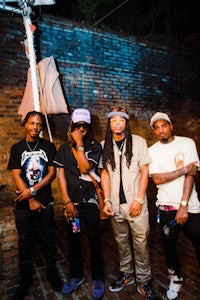 a group of men standing in front of a brick wall
