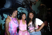 three women posing for a photo in front of a mural