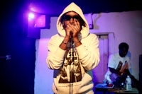 a man in a white hoodie singing into a microphone